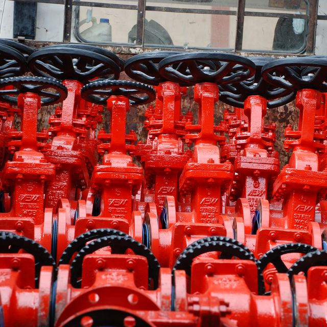 Rows of red cast gate valves with handwheels at the AEW works